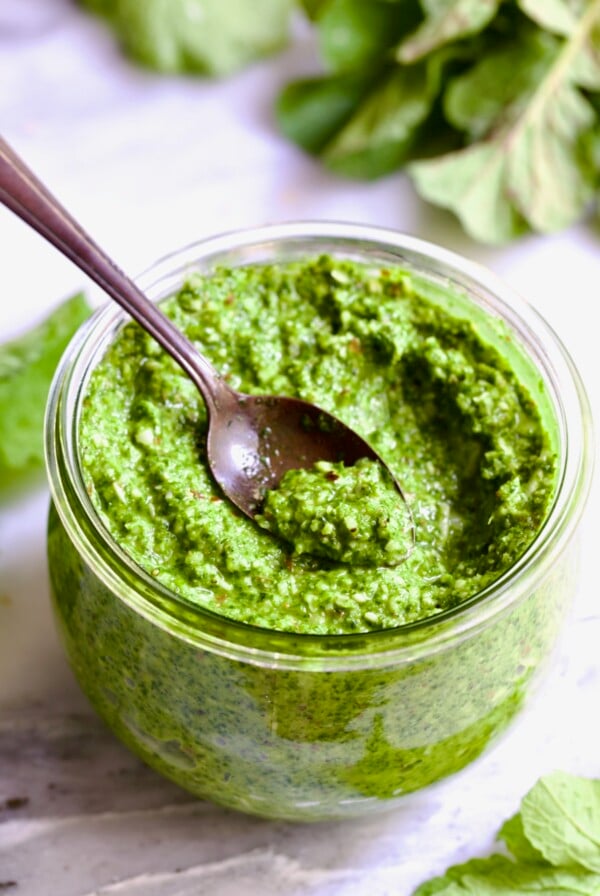 Radish Greens Pesto in glass jar with spoon scooping some up.