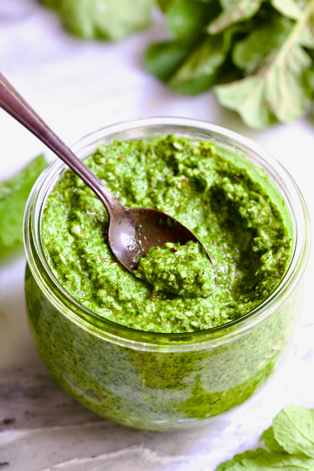 Radish Greens Pesto in glass jar with spoon scooping some up.