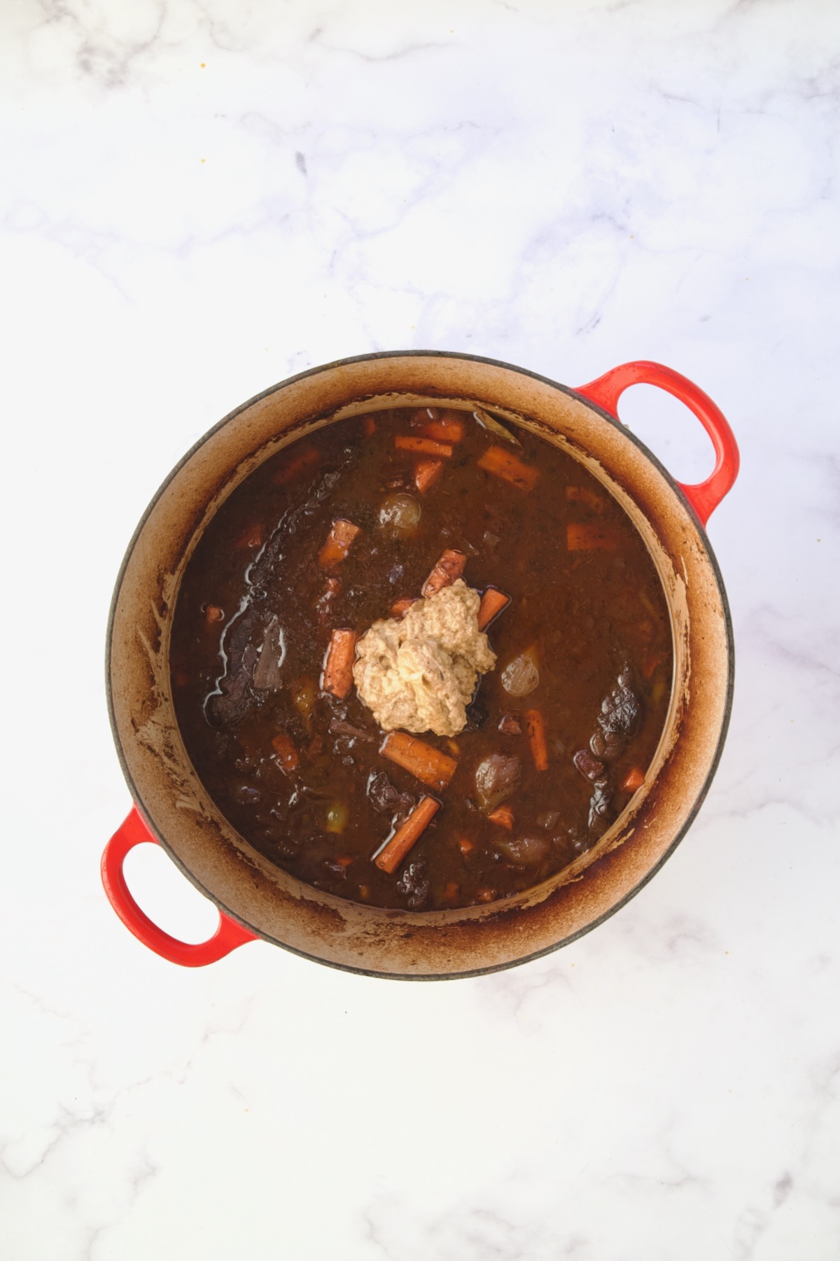 Thickening blend added to recipe in red Dutch oven.