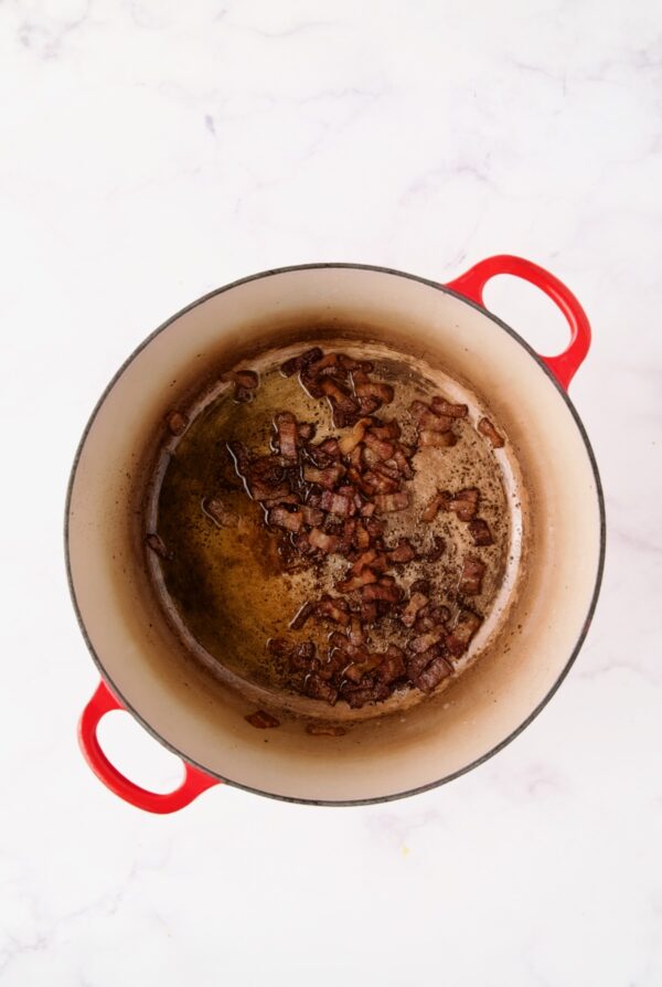 Browned bacon in red Dutch oven.