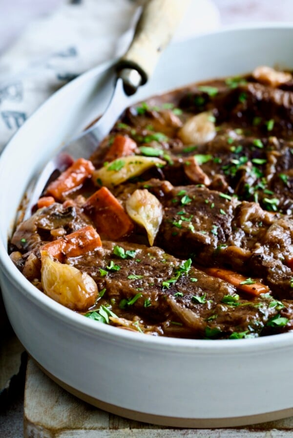 Short Ribs Bourguignon in white oval serving dish with meat fork.