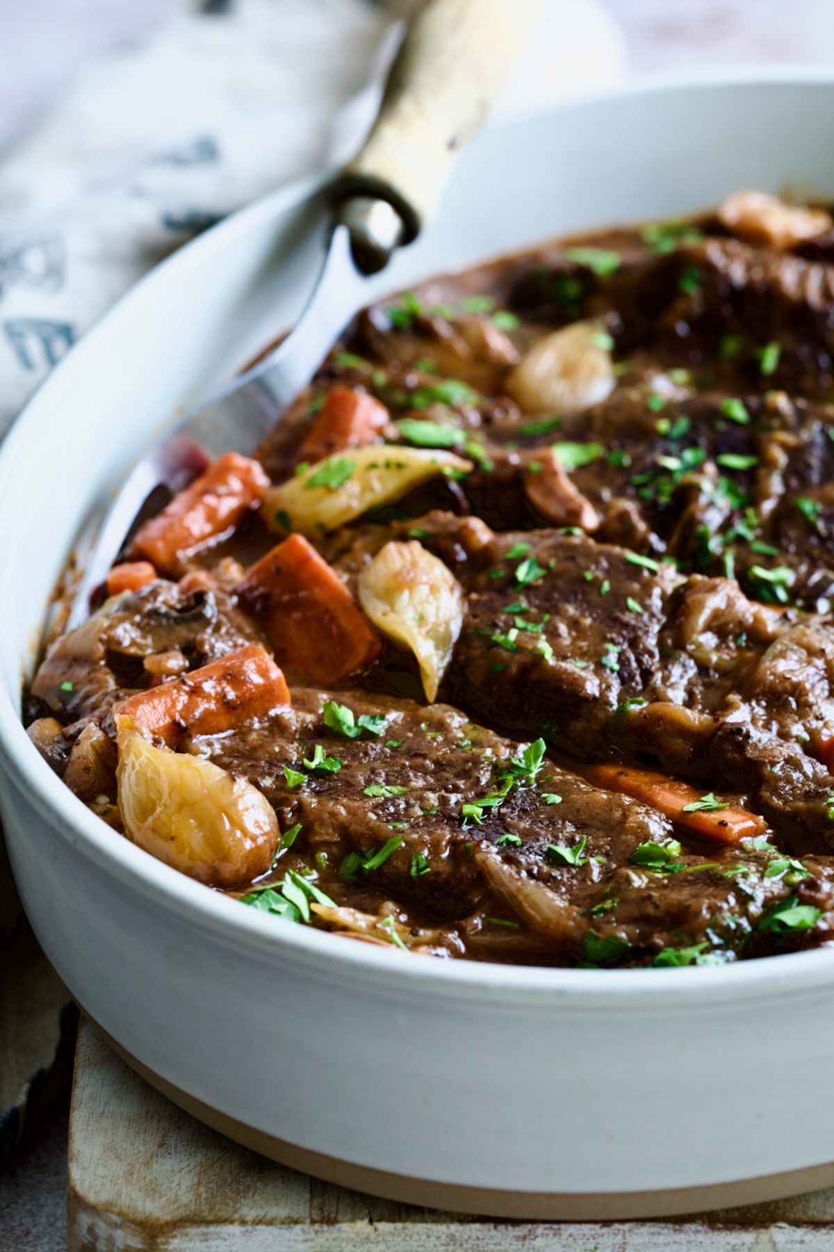 Short Ribs Bourguignon in white oval serving dish with meat fork.