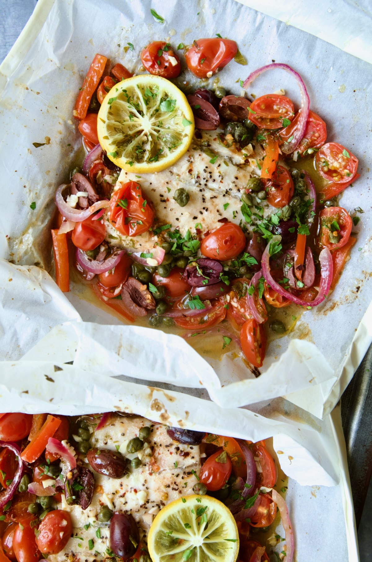 Parchment paper packages opened to reveal baked fish.