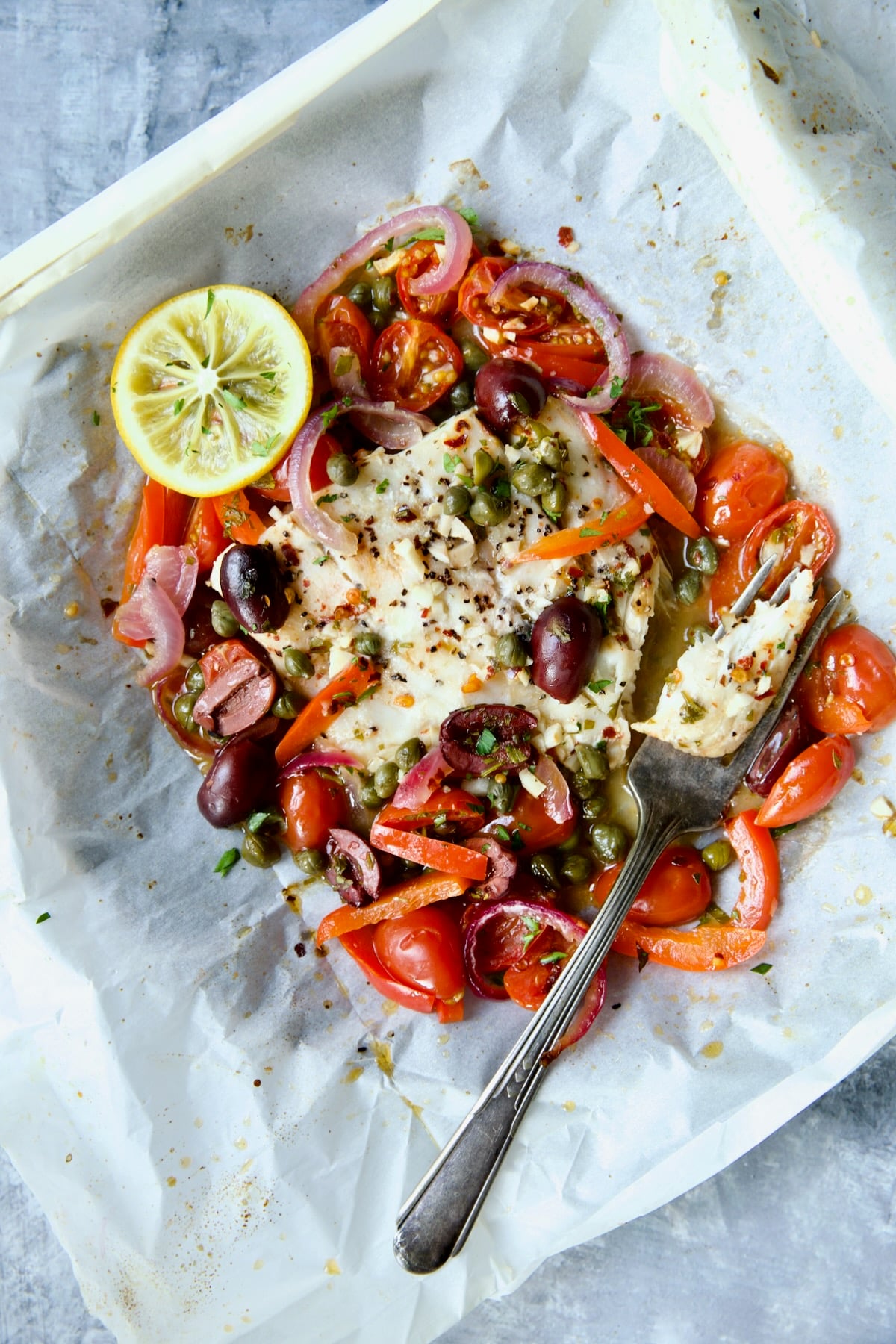Mediterranean Fish en Papillote opened to reveal baked fish with a piece of the fish on a fork.