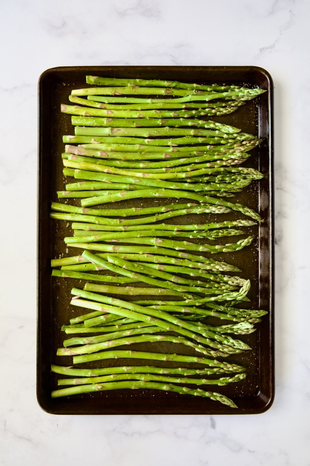 Asparagus on rimmed baking sheet before being roasted.