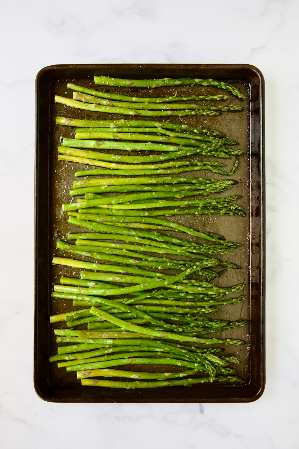 Roasted asparagus on rimmed baking sheet.