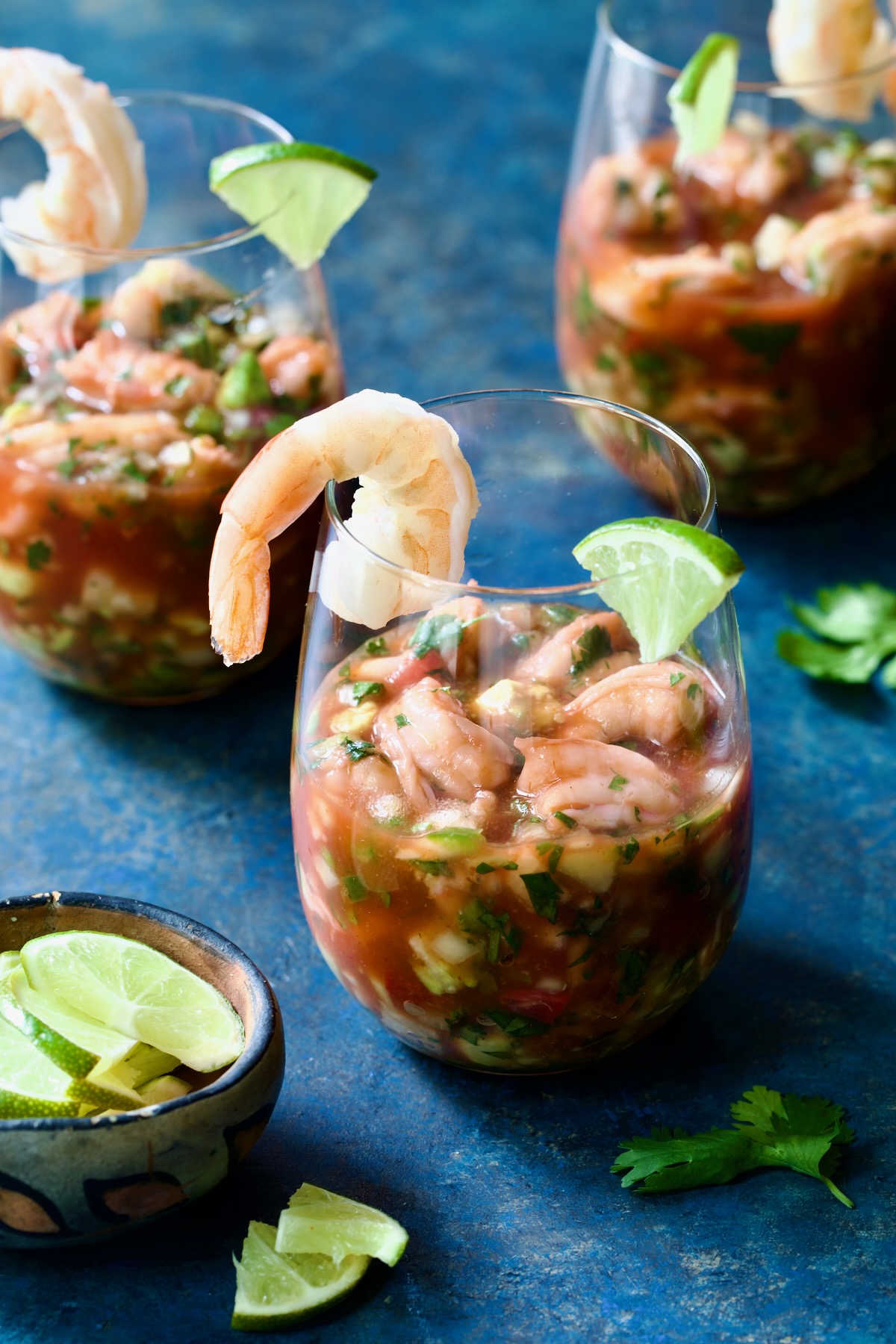 Three glasses of Mexican Shrimp Cocktail garnished with lime wedges.