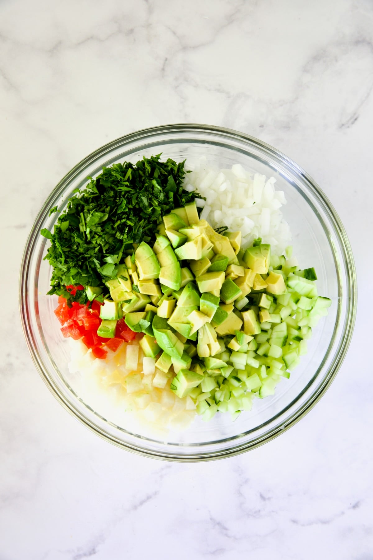 Vegetables in glass bowl for shrimp cocktail before being stirred.
