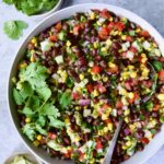 Southwestern Salad with beans, corn and other vegetables in round bowl with cilantro and lime.