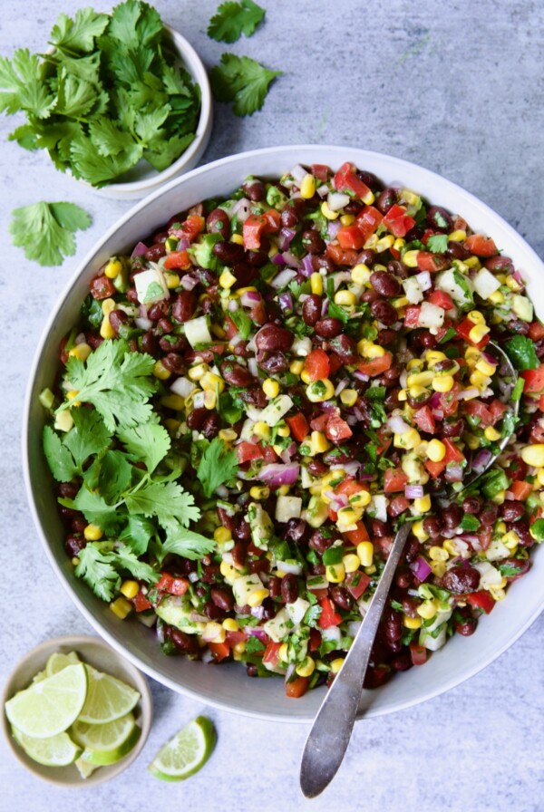 Southwestern Salad with beans, corn and other vegetables in round bowl with cilantro and lime.