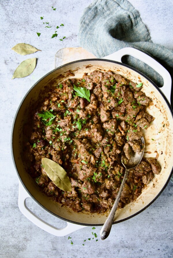 Beef Tips in Beer Sauce in white enamel cast iron skillet.