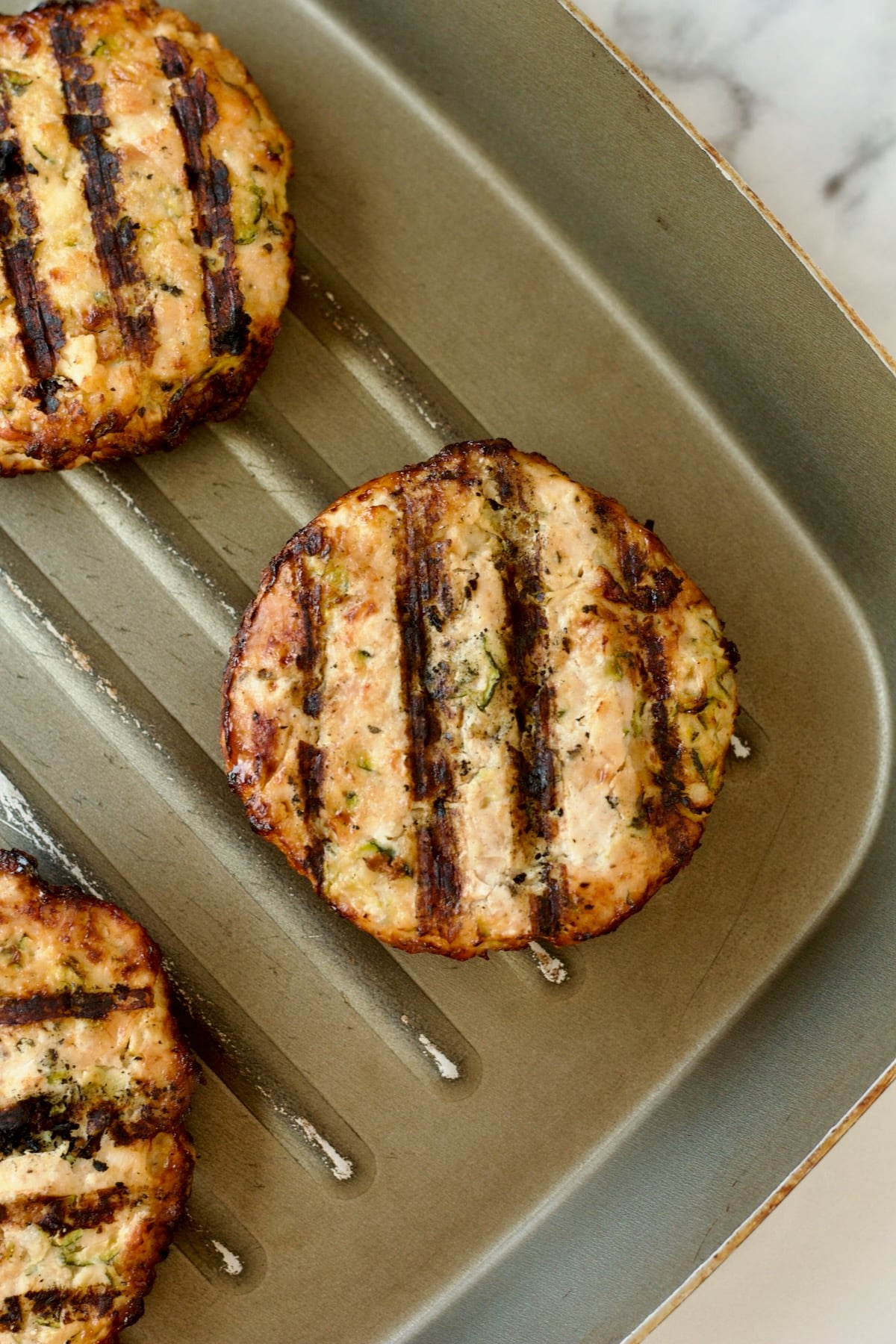 Grilled chicken burgers on grill pan.
