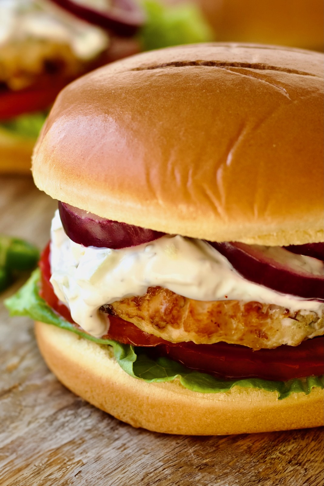 Ground Chicken Burgers with Spicy Tzatziki on wood surface.