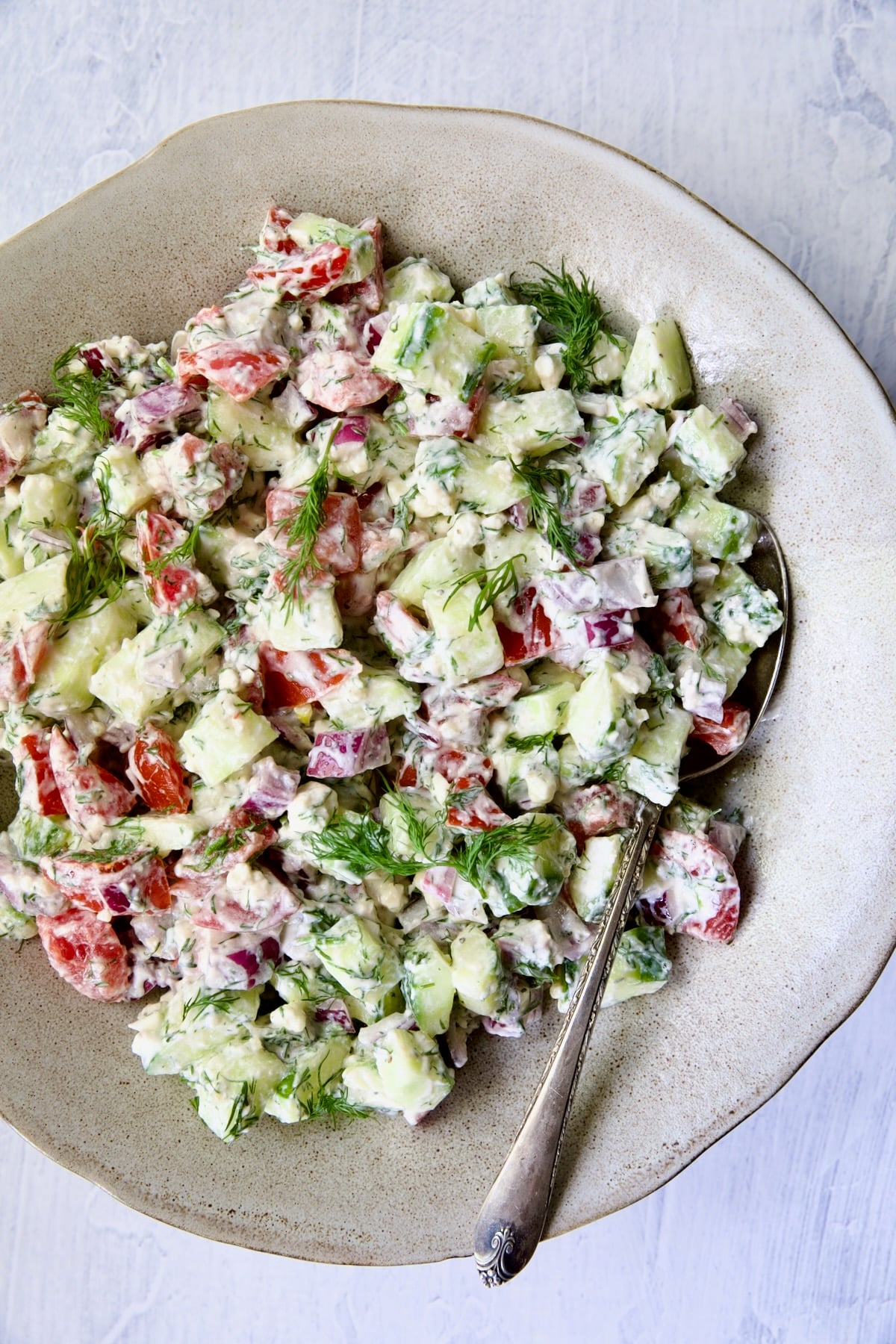 Cucumber Tomato Feta Salad in salad bowl with serving spoon.