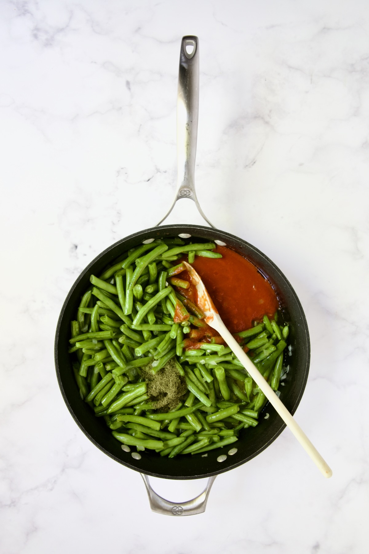 Green beans with tomato sauce and dill in nonstick skillet.