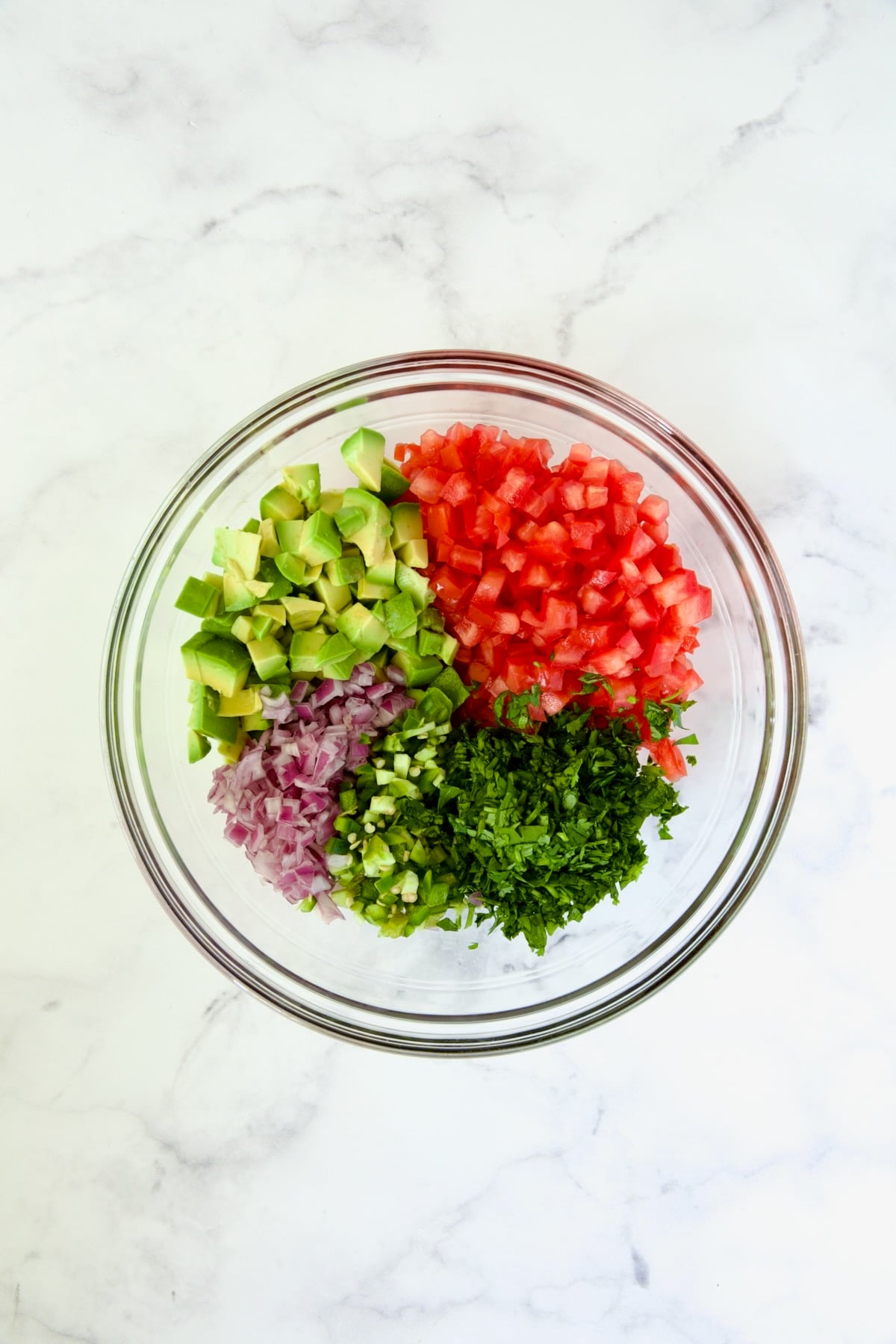 Glass bowl of ingredients for salsa.