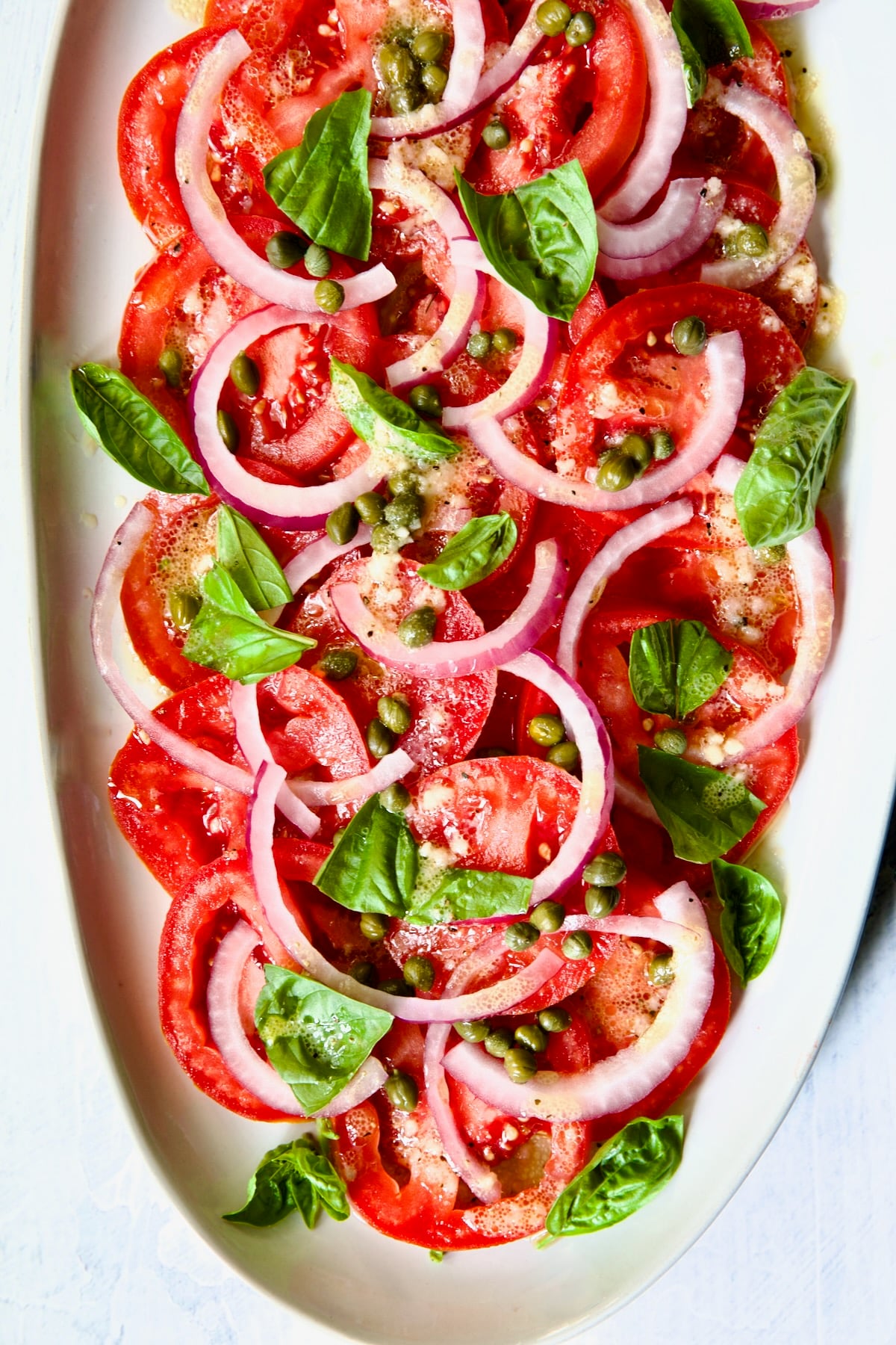 Tomato Onion Salad on white oval platter.