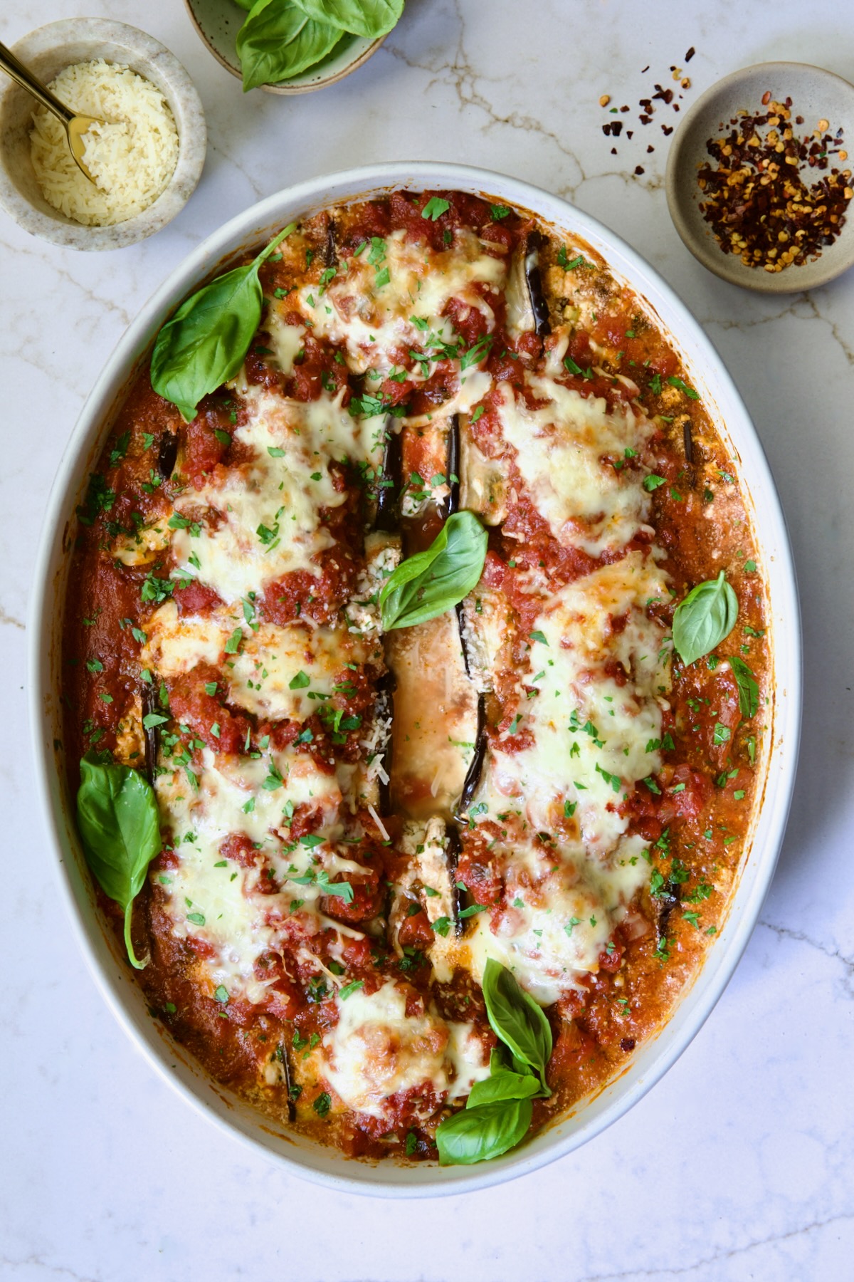 Baked Four-Cheese Eggplant Rollatini garnished with fresh basil.