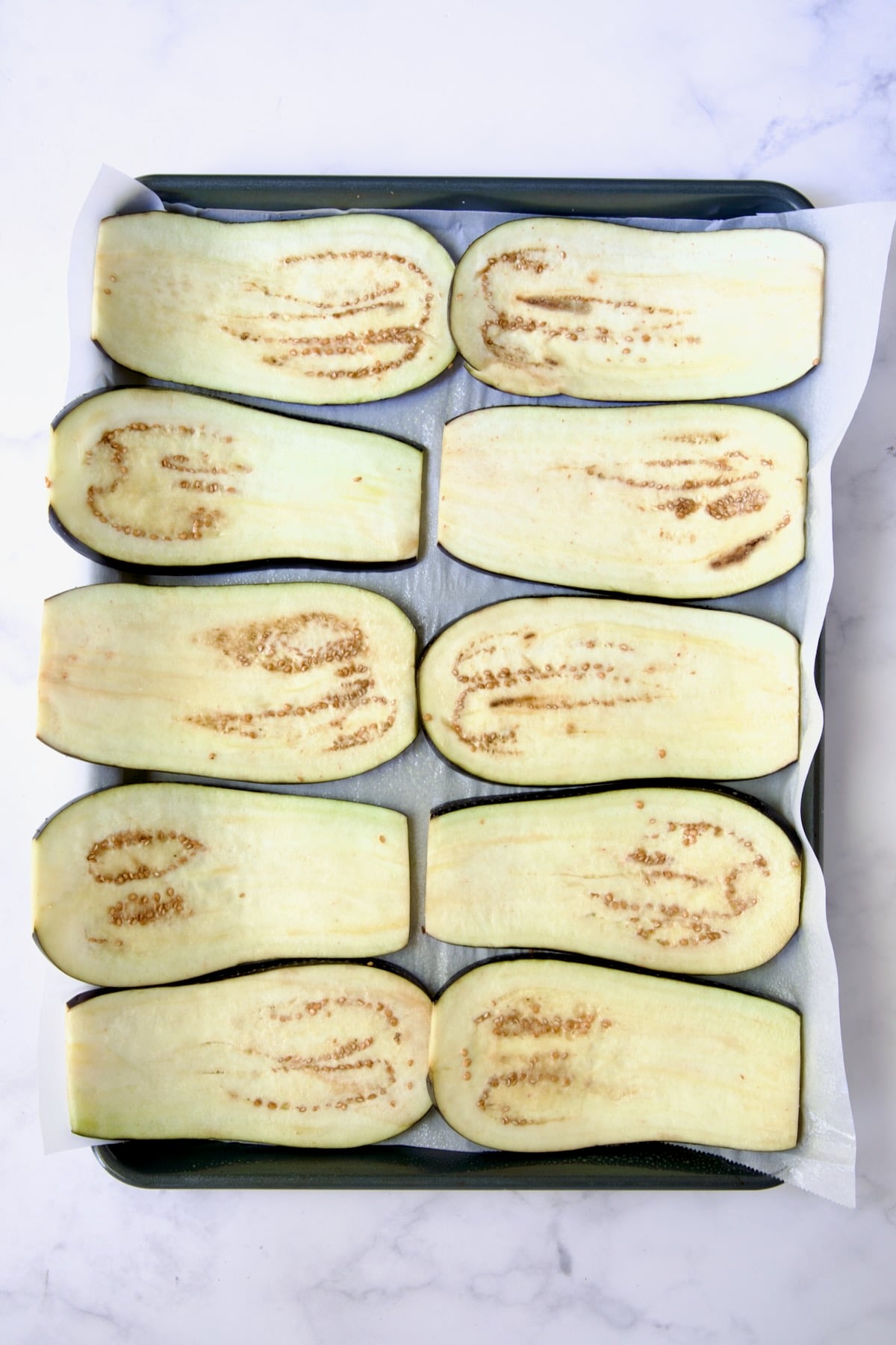 Ten eggplant slices on parchment paper-lined baking sheet.