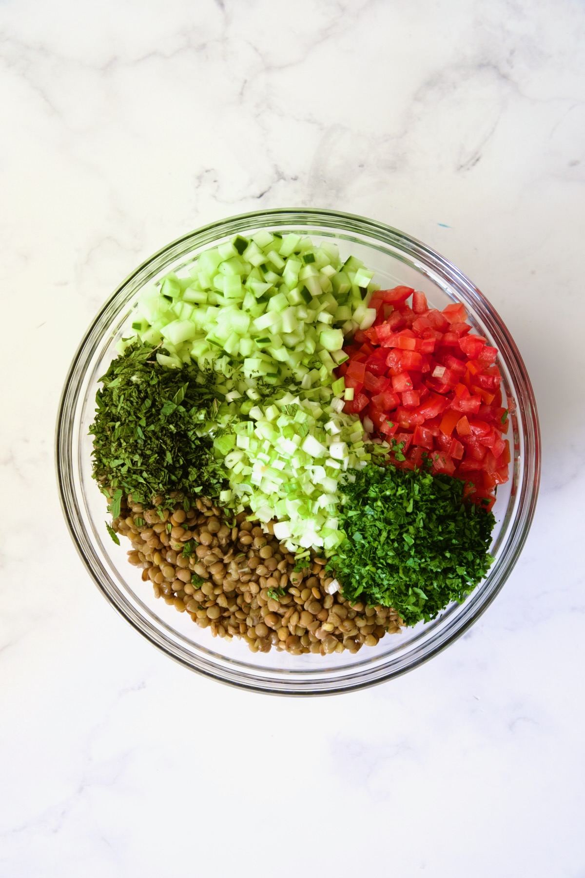 Ingredients for Lentil Tabbouleh in glass bowl before being mixed together.