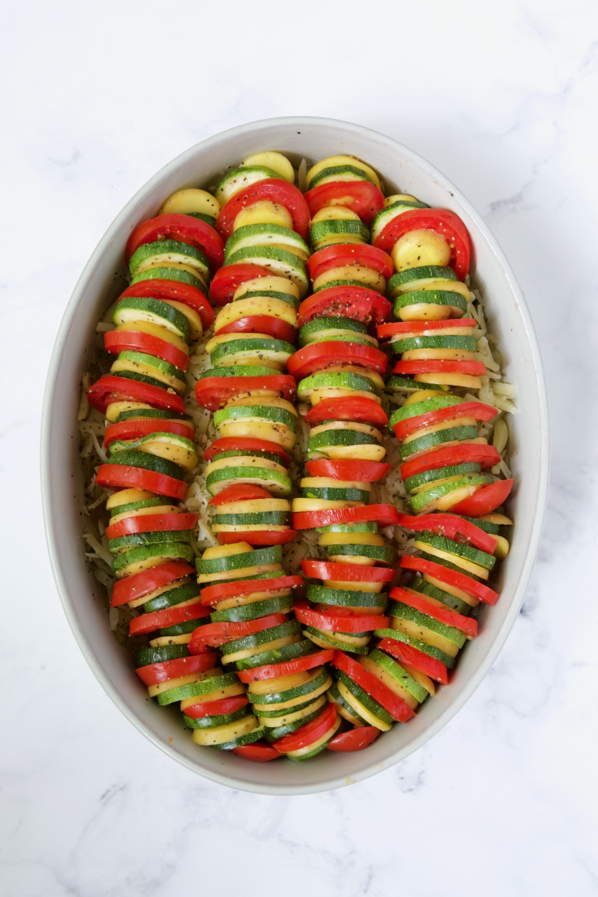 Tomatoes, zucchini and Yukon Gold potatoes in oval baking dish.
