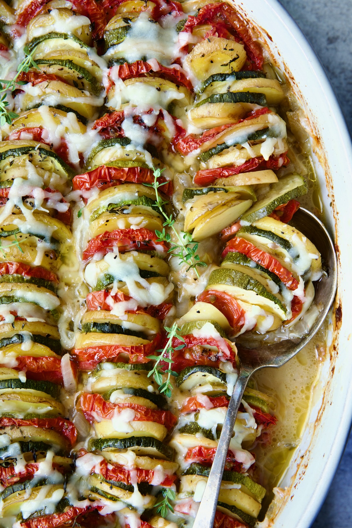 Vegetable Tian in oval baking dish with serving spoon.