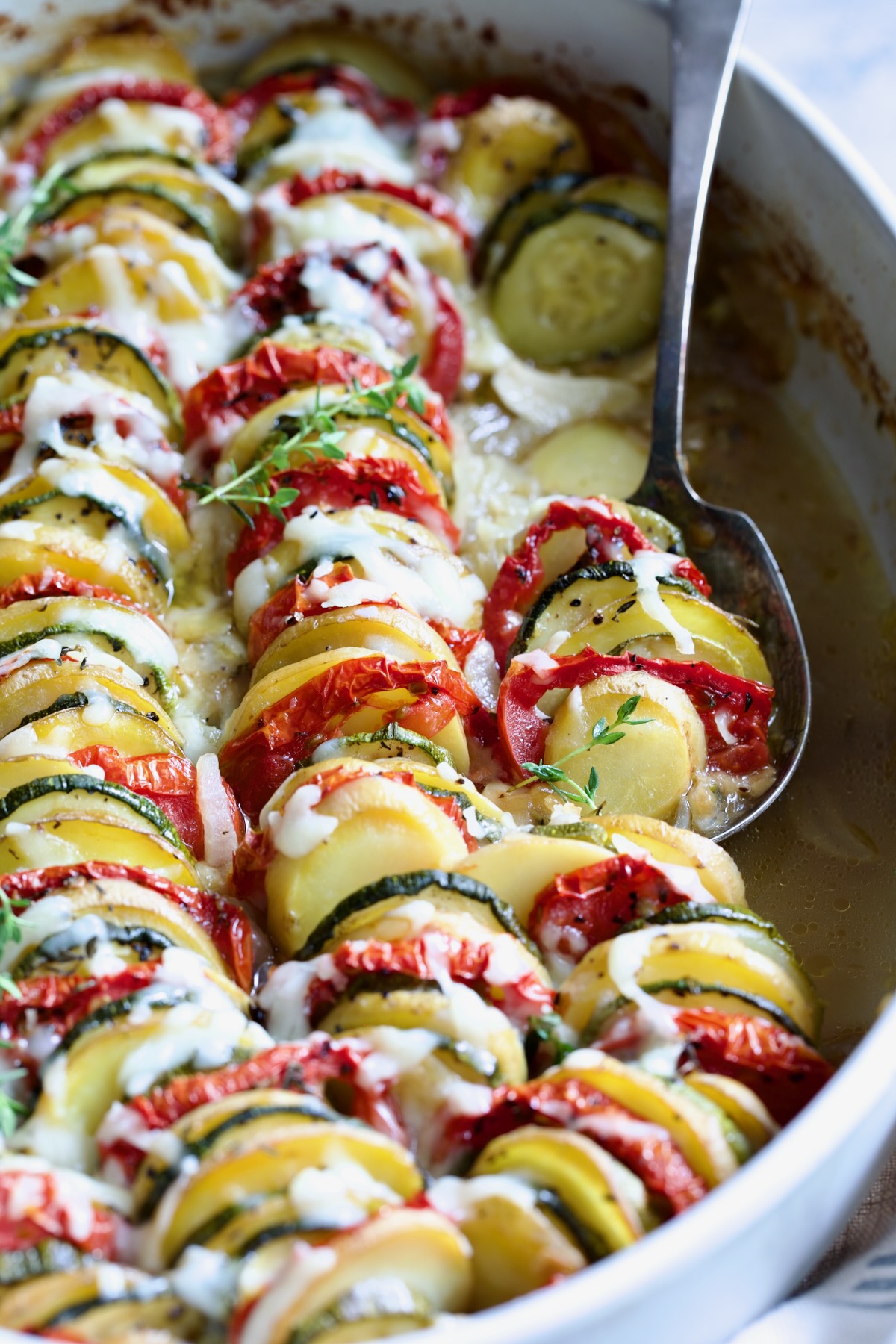 Vegetable Tian in oval baking dish with serving spoon.