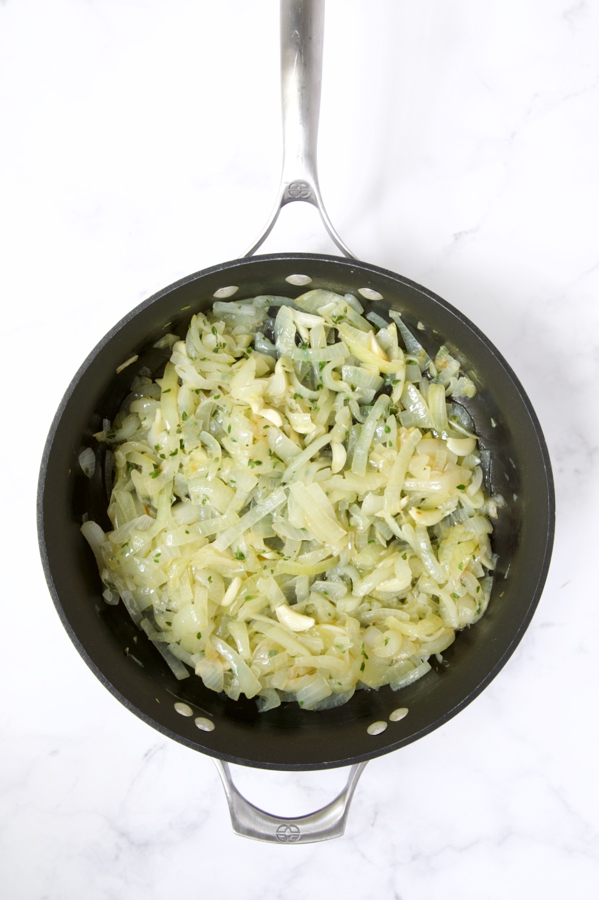 Cooked onions with garlic and fresh thyme added in nonstick skillet.