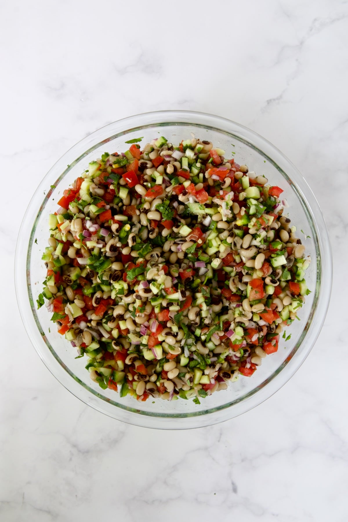 Ingredients for Black-Eyed Pea Salad in glass bowl after being combined together.