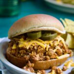 Chicken Sloppy Joes on plate with grated cheese and jalapeno slices.