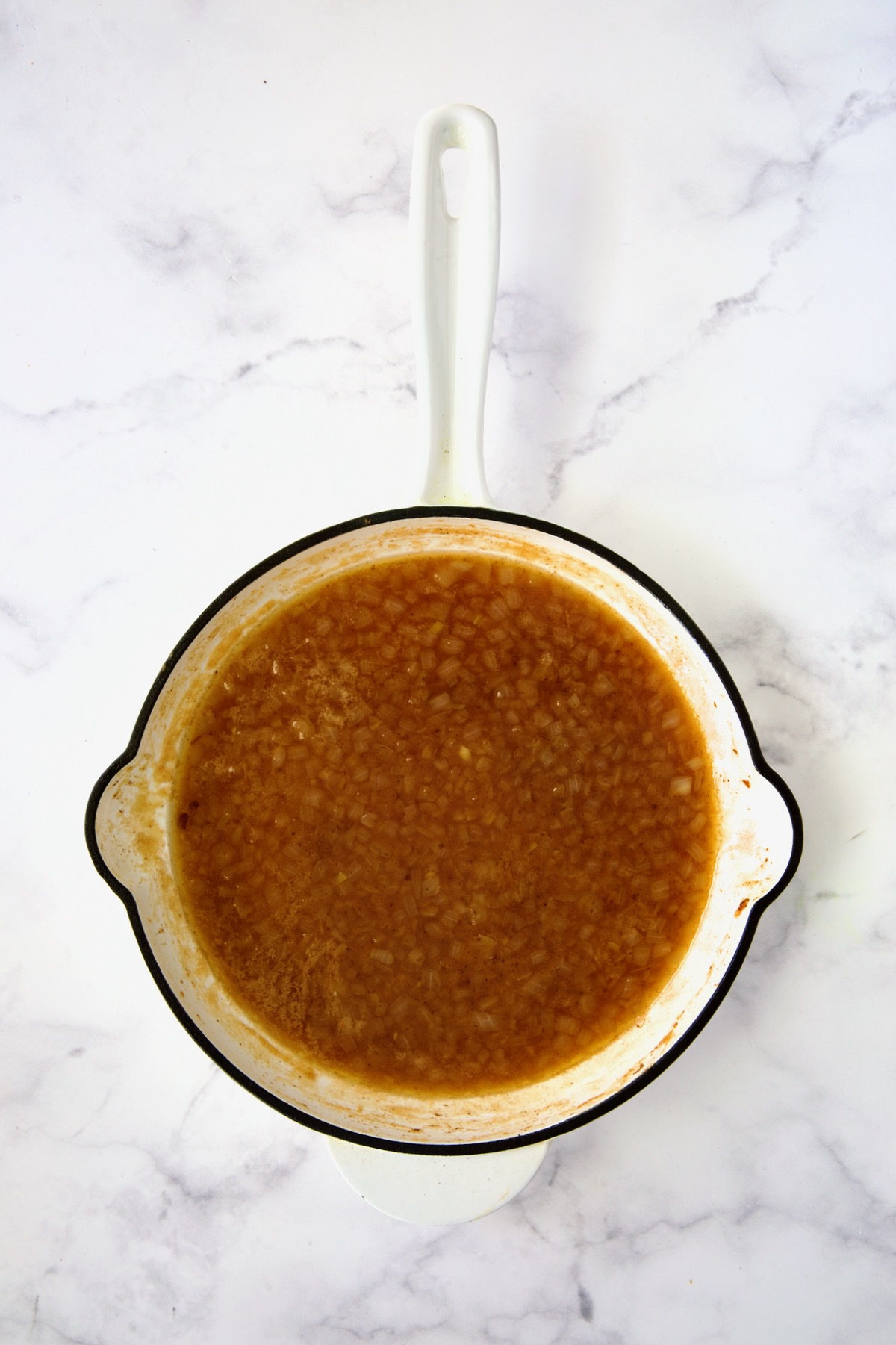 Cooked salad dressing for German Potato Salad in white enamel cast iron skillet.