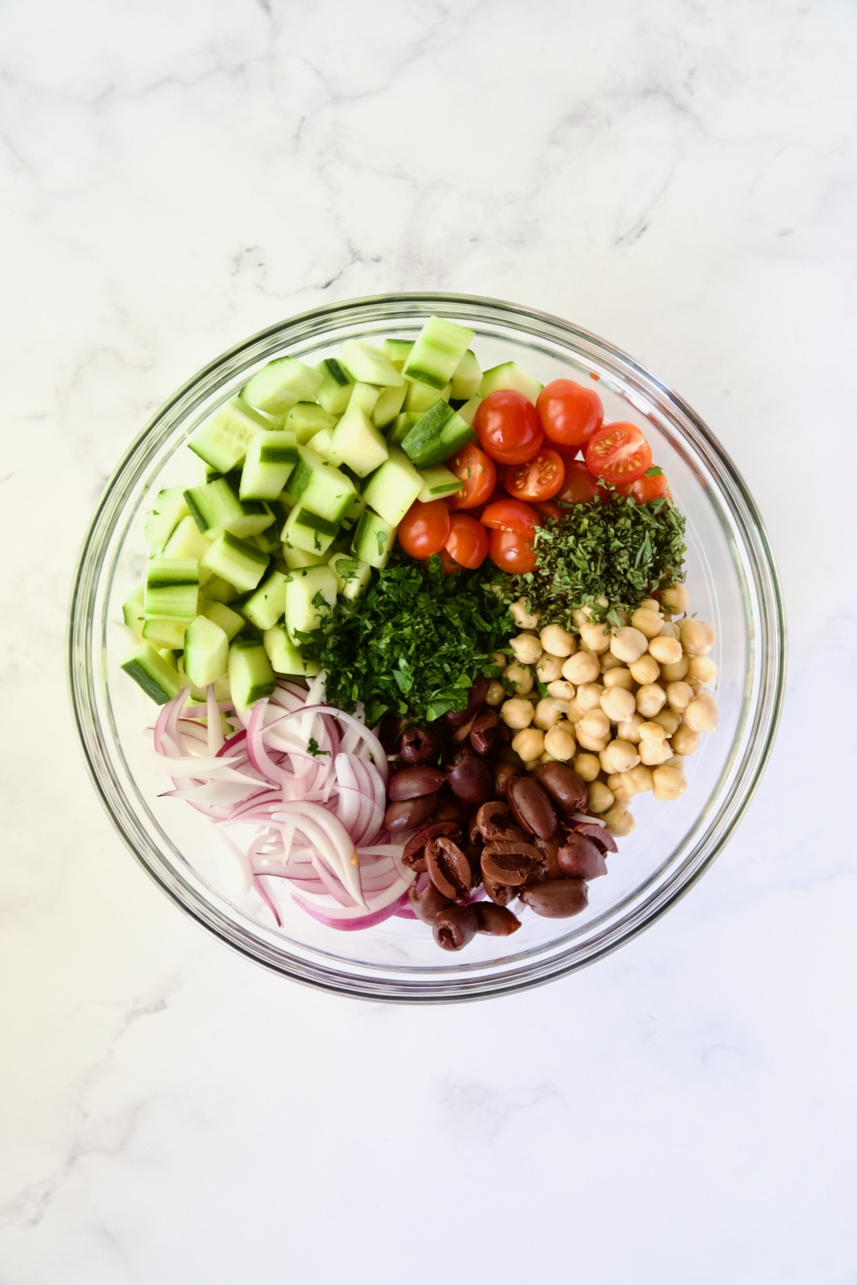 Ingredients for Greek Cucumber Salad in glass bowl before being mixed together.