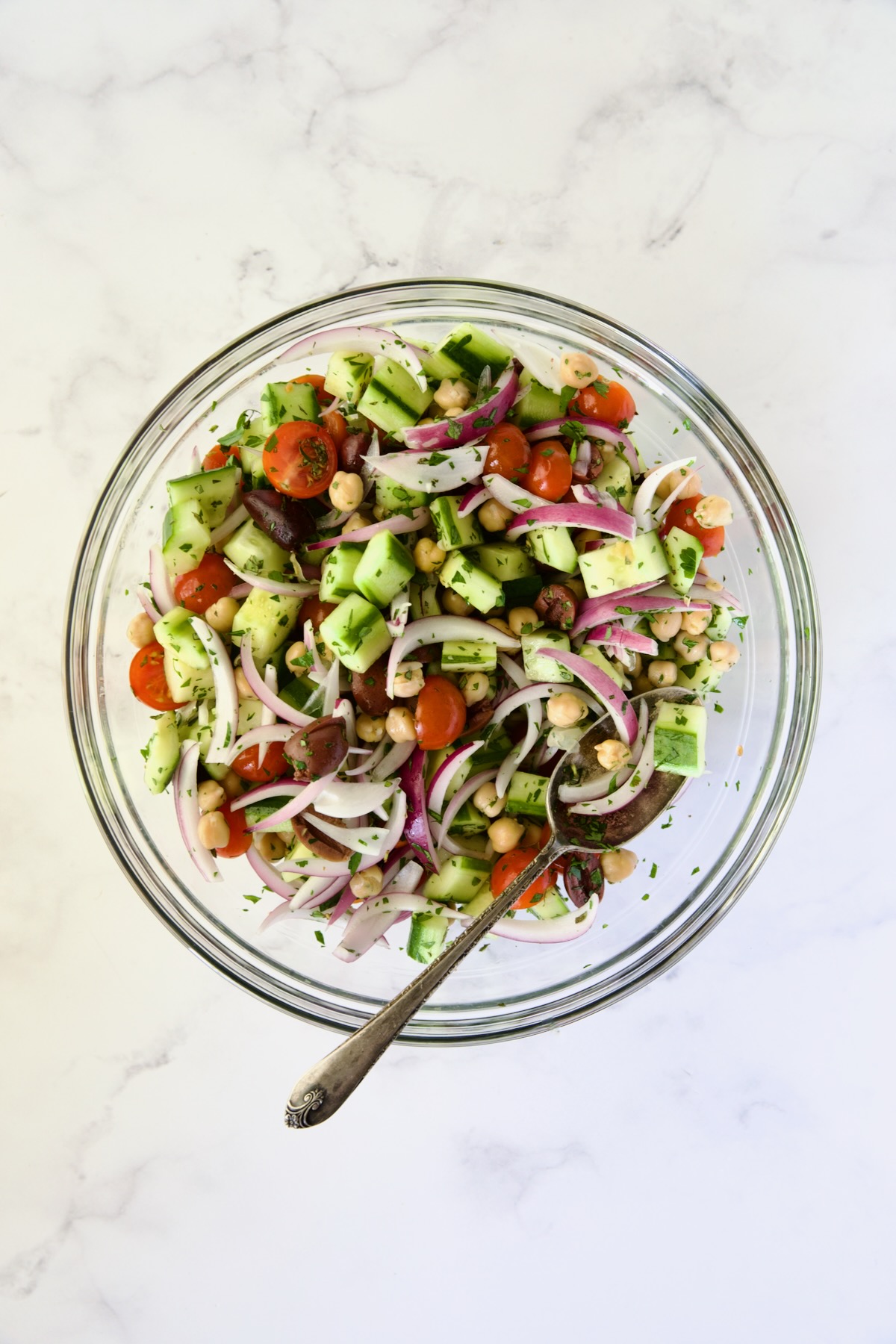 Ingredients for Greek Cucumber Salad in glass bowl after being mixed together.