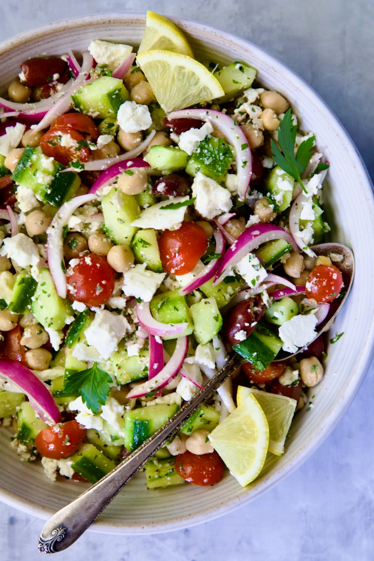 Greek Cucumber Salad in white bowl with serving spoon.