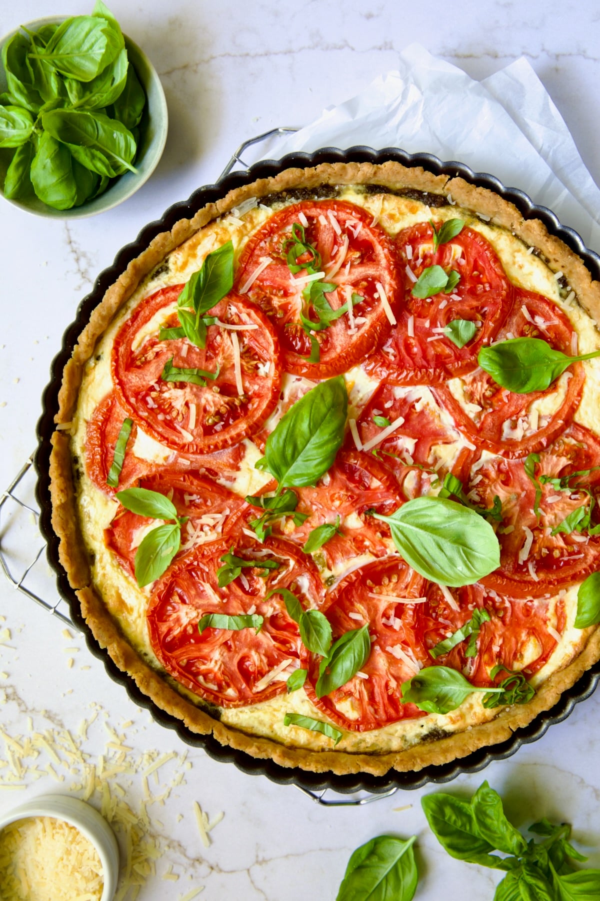 Whole Tomato Tart with Ricotta and Cheese on cooling rack garnished with fresh basil leaves.