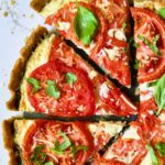 Tomato Tart with Ricotta and Cheese sliced into wedges and garnished with fresh basil leaves.
