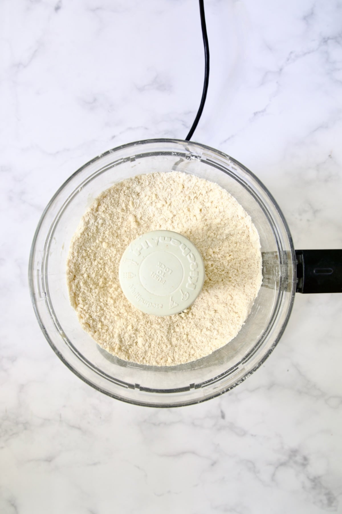 Butter cubes, flour, salt and pepper in bowl of food processor blended together to make a coarse meal.