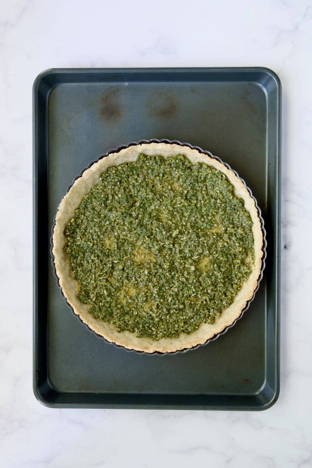 Pesto spread over bottom of tart crust.
