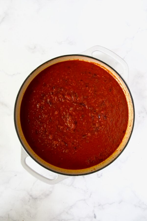 Marinara and crushed tomatoes added to white enamel cast iron skillet.