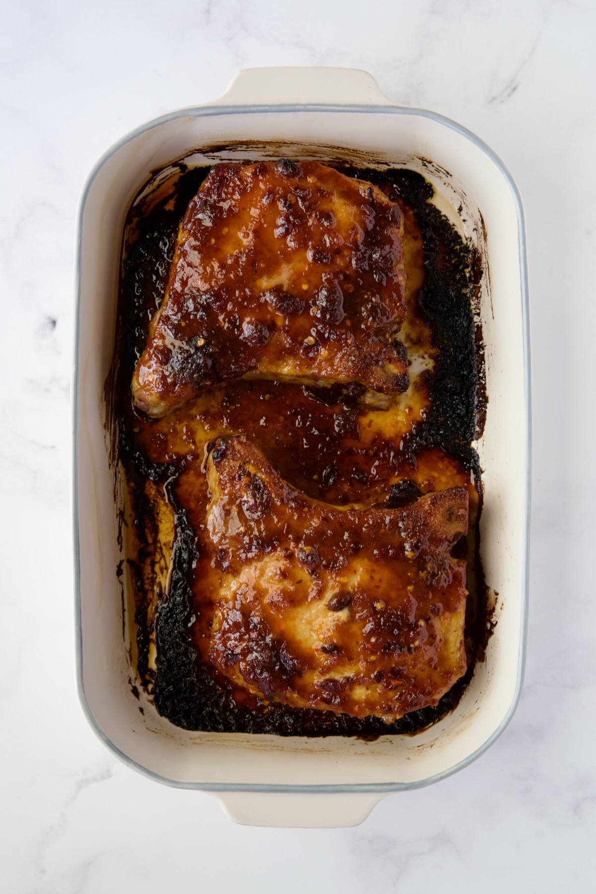 Two baked Asian Pork Chops in baking dish.