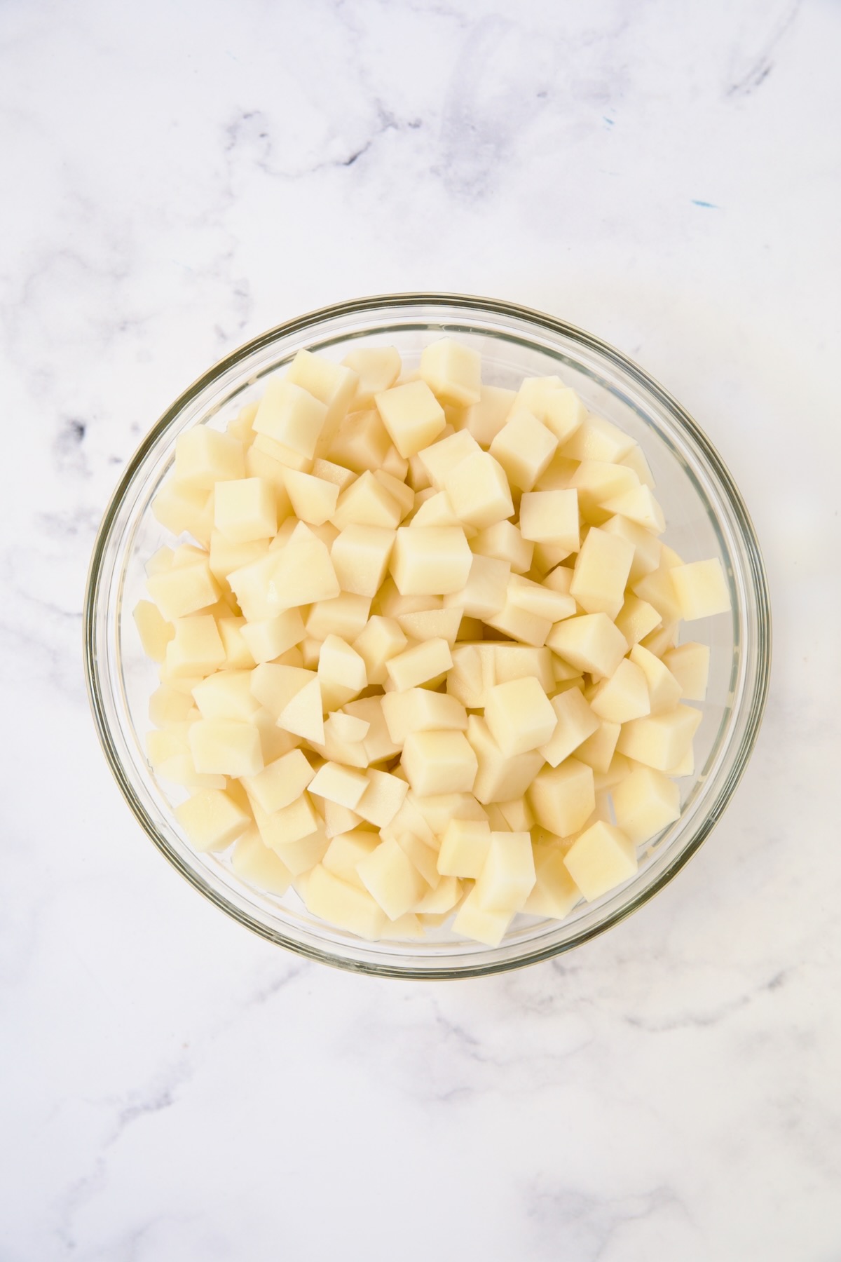 Cubed potatoes in glass bowl.