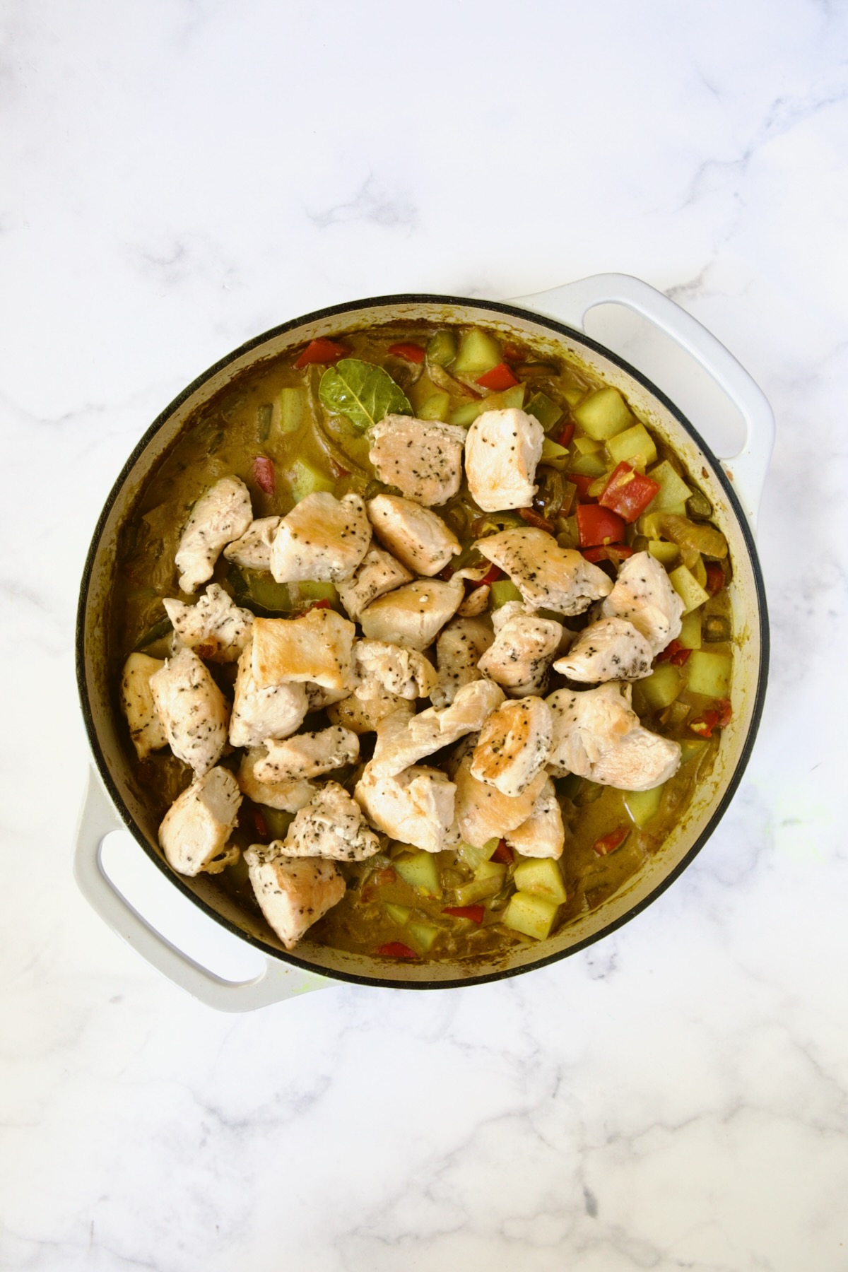 Chicken added back to curry in white enamel cast iron skillet.