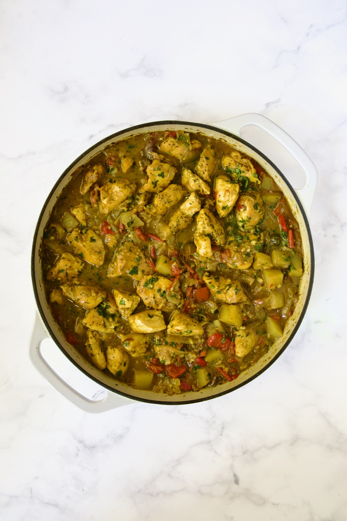 Finished Chicken and Potato Curry in white enamel cast iron skillet.