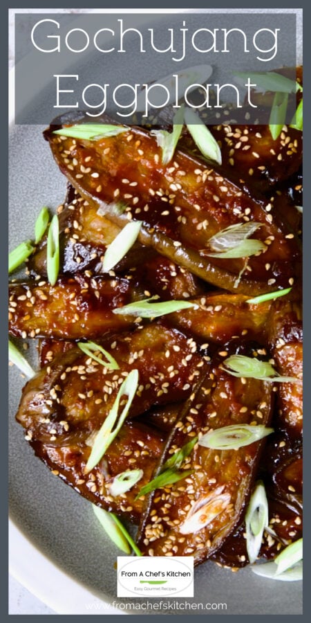 Gochujang Eggplant on gray and white plate garnished with sesame seeds and thinly sliced scallion.
