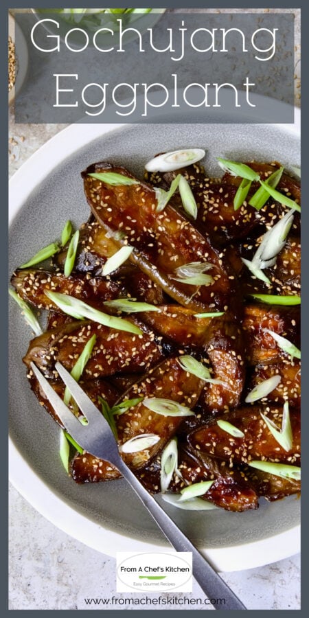 Gochujang Eggplant on gray and white plate garnished with sesame seeds and thinly sliced scallion.