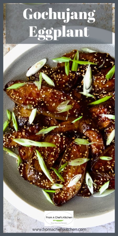 Gochujang Eggplant on gray and white plate garnished with sesame seeds and thinly sliced scallion.