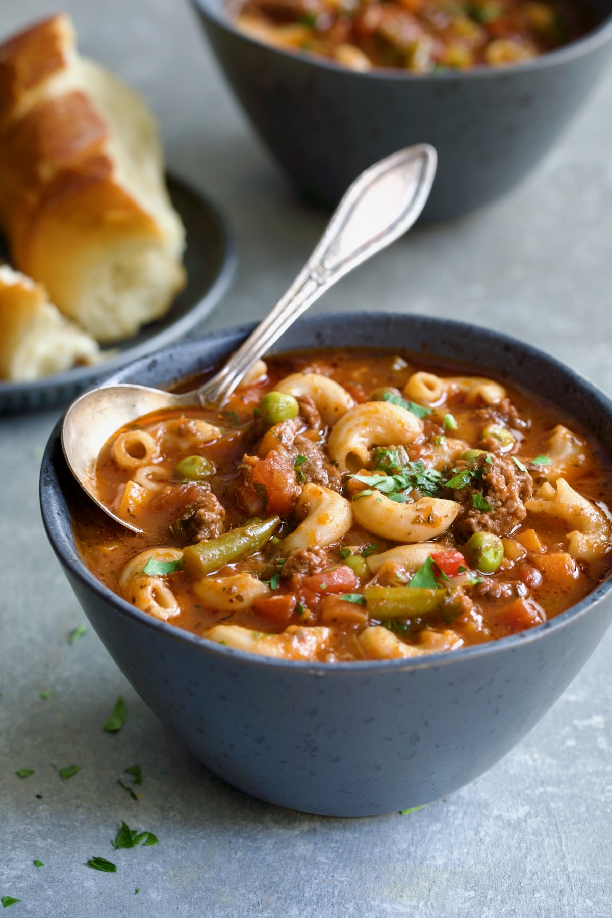 Hamburger Vegetable Soup in gray bowl with soup spoon.