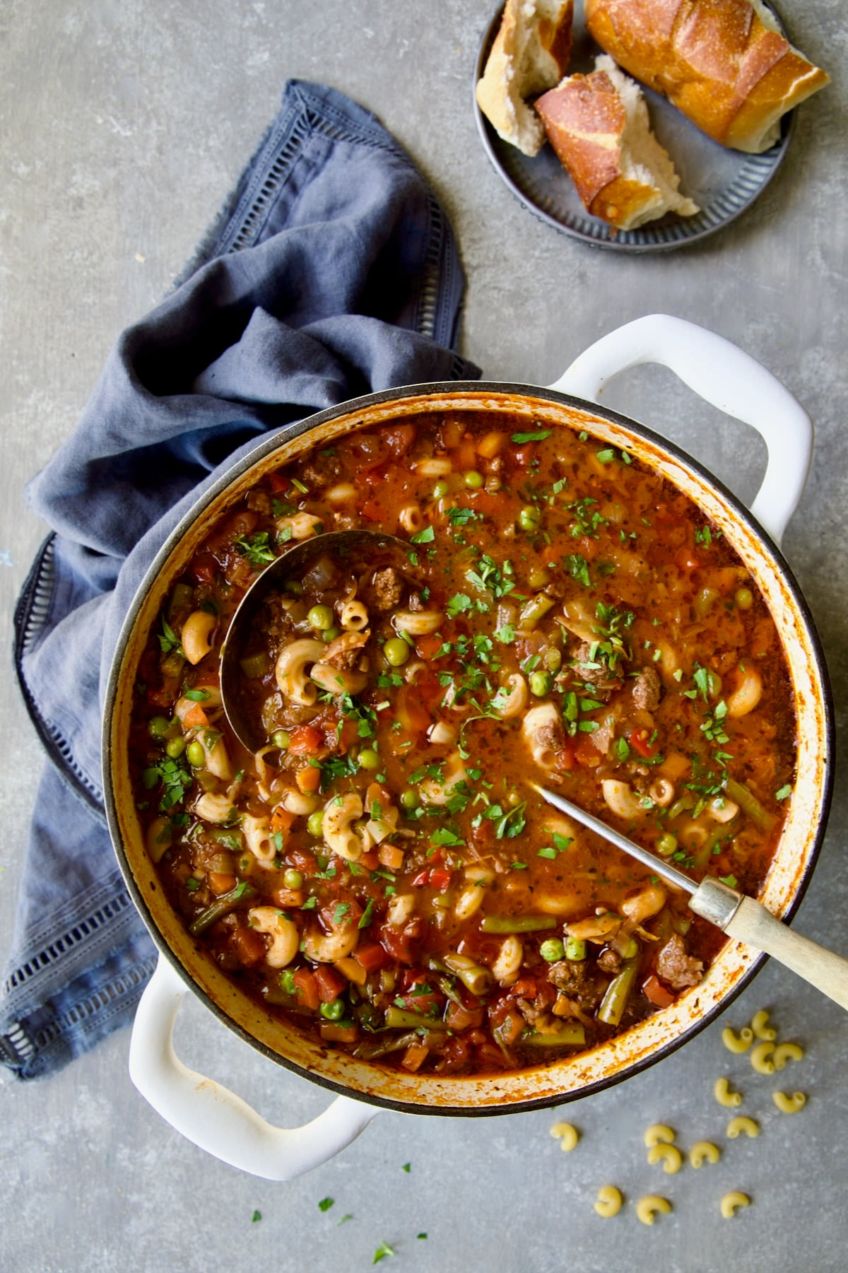 Hamburger Vegetable Soup in white Dutch oven with soup ladle.