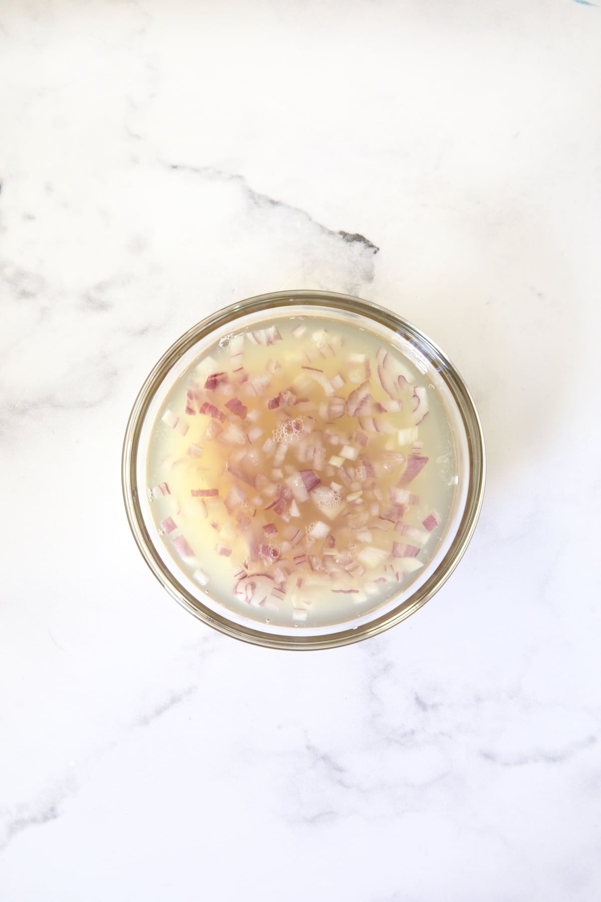 Shallots and lemon juice in glass bowl.