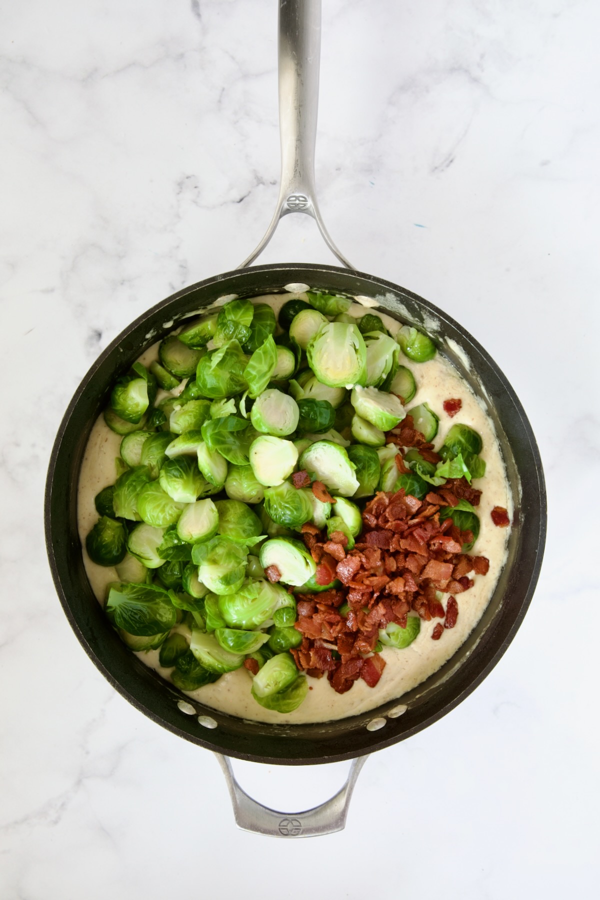 Blanched Brussels sprouts and bacon added to cheese sauce in nonstick skillet.